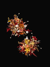 CAMELLIA's burgundy Theater Style Wedding Flower Rings feature two intricate handcrafted arrangements with red, yellow, and white flowers accented by pearls on a black background. Ideal for a custom adjustable ring size.